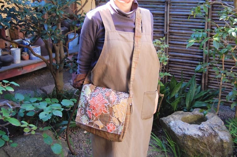 It is a shoulder hanging bag made by remake of the old cloth of tsumugi. The bag, embroidered in warm colors on high-quality tsumugi fabric, becomes softer and more familiar as you use it. Because it is a handmade one point, it becomes the present article only.